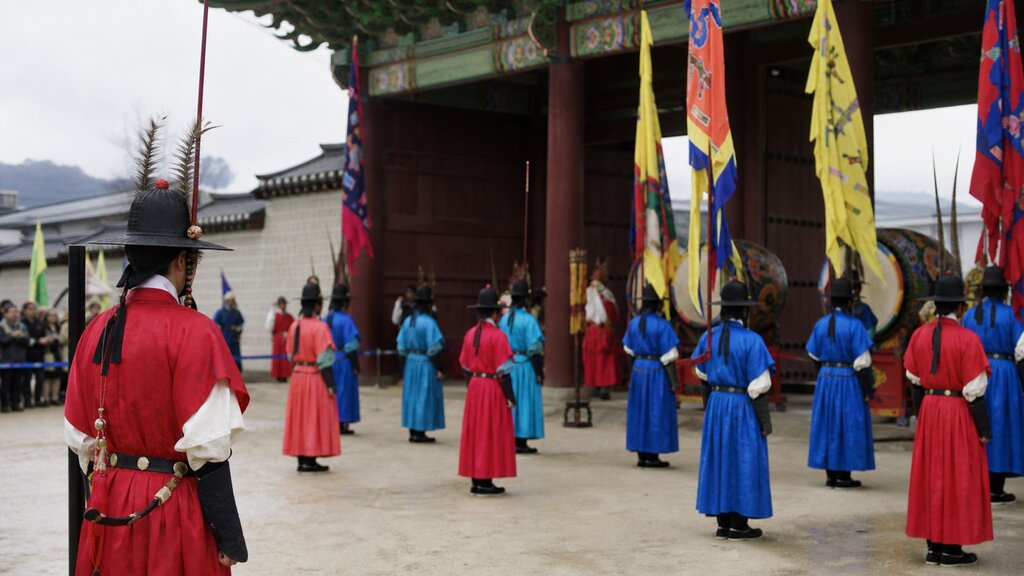 Guards in traditional Joseon-era uniforms with drums and banners at the changing of the guard by the palace gate