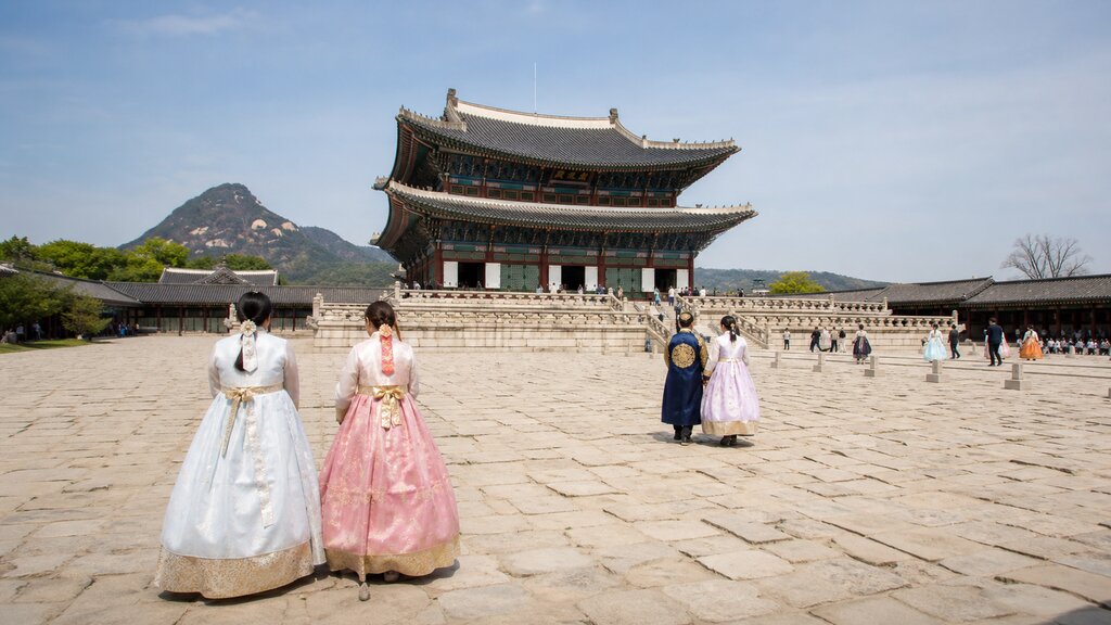 Gyeongbokgung's main throne hall with visitors in colorful hanbok crossing the stone courtyard
